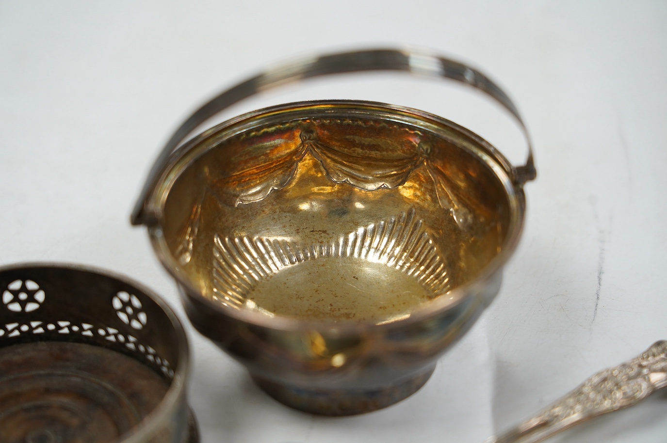 A George III silver small epergne basket, London, 1800, diameter 80mm, a large William IV silver caddy spoon and an Old Sheffield plate sauce bottle coaster. Condition - fair